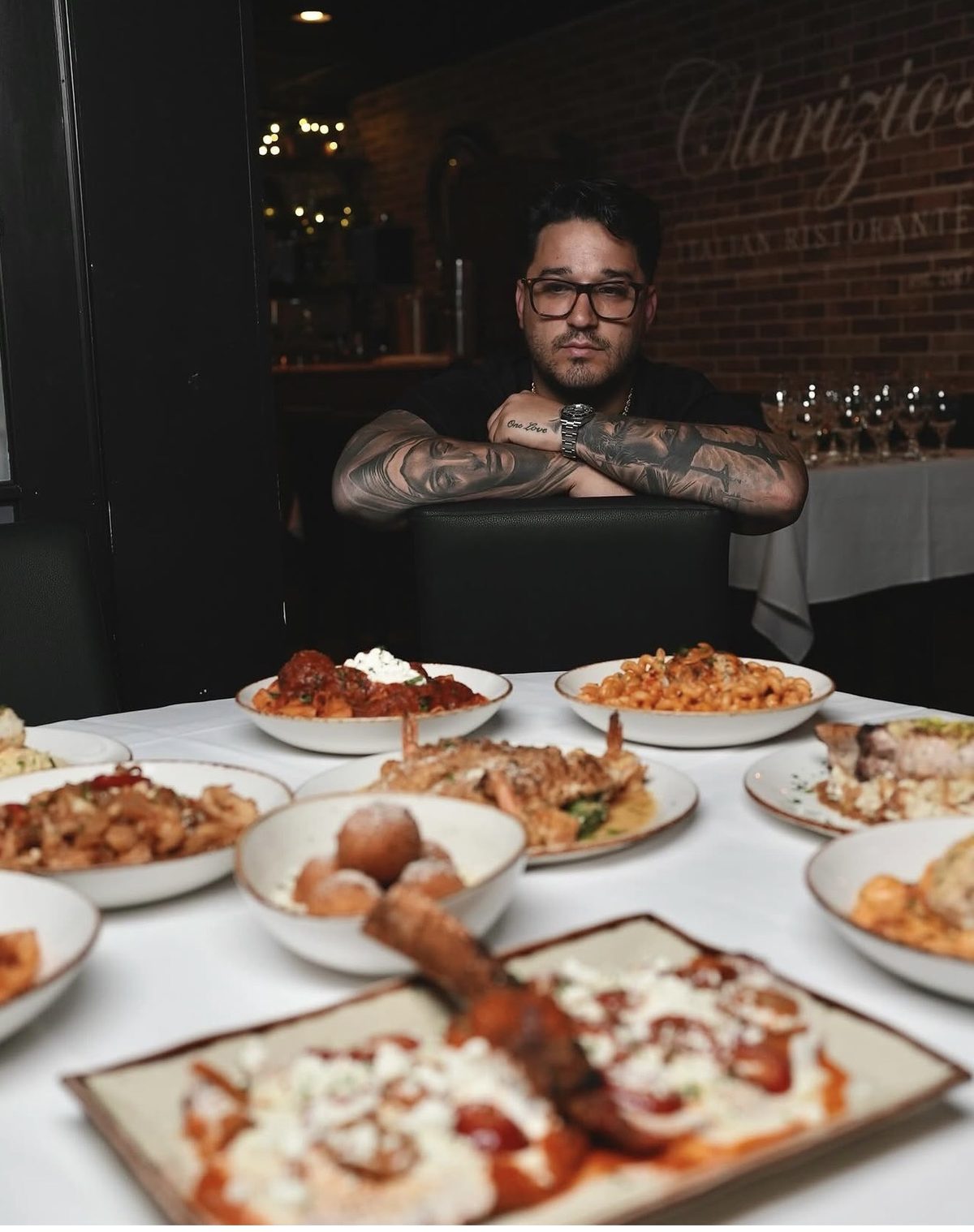 A guest seated at a table at Clarizio&rsquo;s looking over the dishes in front of him.